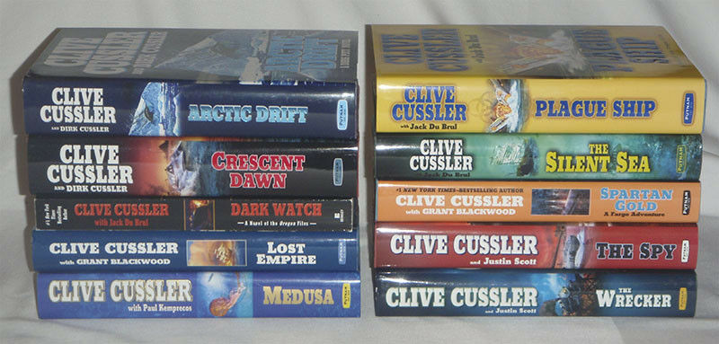 pick one - Clive Cussler - DIRK PITT - hardcover books - HC DJ firewood - one pb - Fresh Stock Dated December 2025